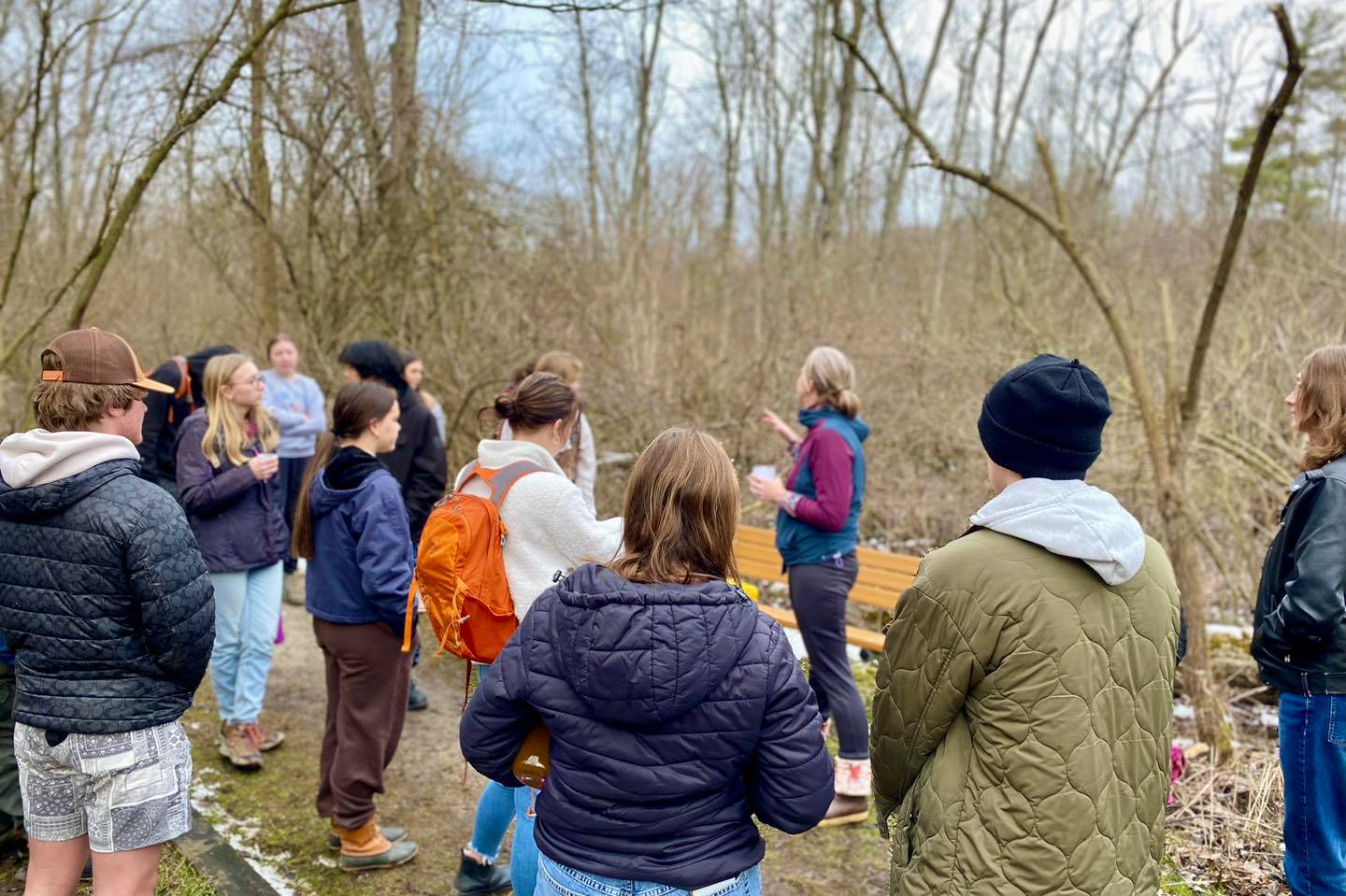 Careerline Tech Students standing listening to a teacher, outside in cold weather next to a forest with snow on the ground